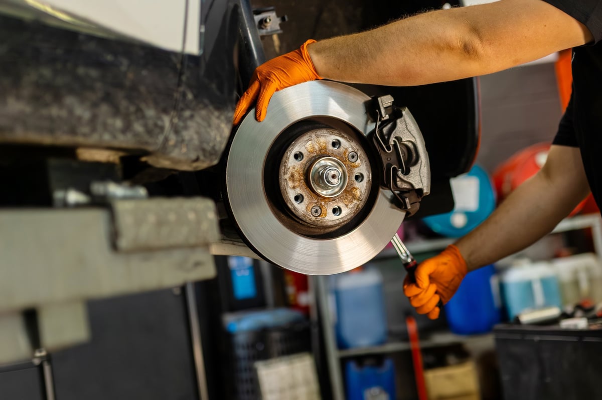 Mechanic installing a new brake disc and caliper assembly on a BMW