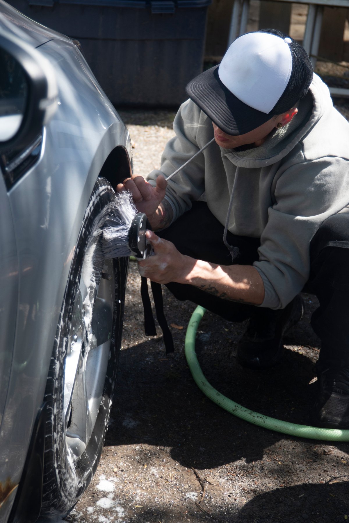 Mobile car wash on a driveway, cleaning a wheel with a brush